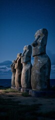 Moai statues on Easter Island watching rising moonlight. Ancient Moai statues standing by the ocean under a night sky with bright moonlight