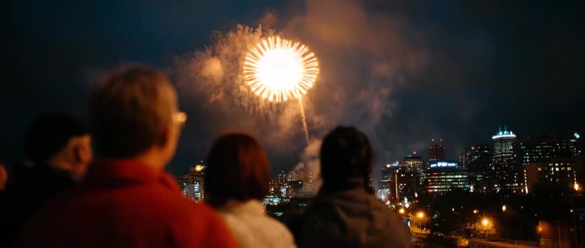Beautiful fireworks explode above a vibrant city skyline at night.