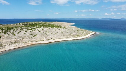 ​Panoramic aerial view of a long rocky peninsula with sparse vegetation stretching into the vibrant turquoise Adriatic sea. Summer coastal scenery.