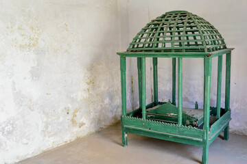 aged green wooden pavilion structure placed at weathered surroundings with textured wall, minimal composition with copy space