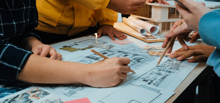 A dynamic workshop scene highlighting collaboration in architecture as diverse individuals engage in sketching blueprints, sharing ideas, and using various materials. SACTR