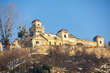 Fototapeta premium Close view of a historic hilltop monastery with stone walls and towers under clear blue sky, highlighting religious architecture and cultural heritage in winter.