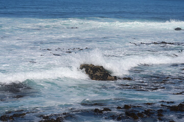 The waves crash against the rocks on the coast.