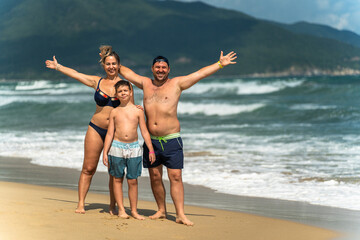 A happy family waves their hands on vacation at the beach and sea
