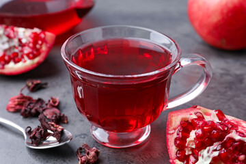 Aromatic pomegranate tea, fresh fruits and dry roselle sepals on grey table, closeup