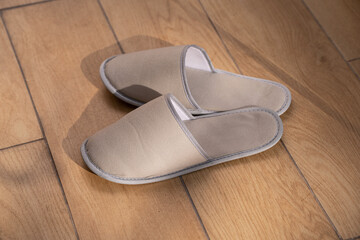 A pair of hotel slippers on the parquet floo