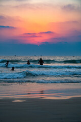 Fototapeta premium Sunset at Colva Goa beach in South India, silhouette of people swimming in Arabian Sea, tropical west coast, Asia, vacation destination