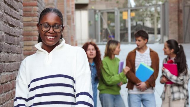 A joyful teenage girl stands confidently while her classmates engage in conversation nearby, embodying friendship and camaraderie in an educational atmosphere filled with youthful energy.