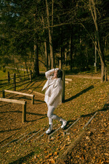 Fototapeta premium Young caucasian woman enjoying autumn forest walk in stylish outfit