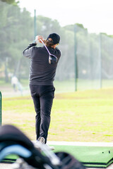 A man is swinging a golf club on a green field