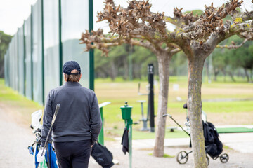 A man is walking with a golf club and a bag