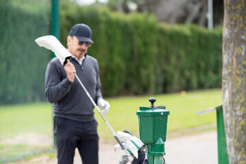 A man in a black shirt and hat is holding a golf club