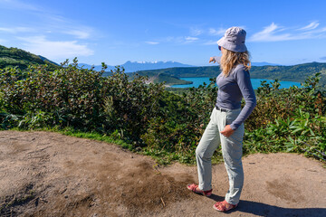A woman stands on a hillside, pointing at the stunning vistas of Russia. Surrounded by lush...