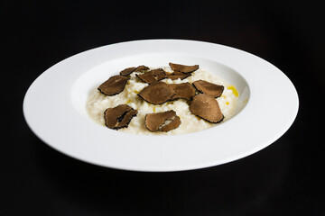Plate of Italian risotto with truffle on a black background. 