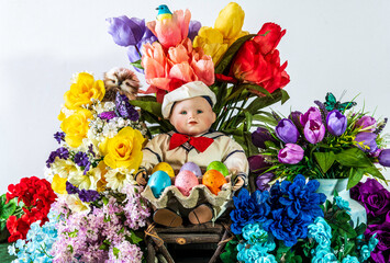 little boy sailor doll holding colored Easter eggs surrounded by spring flowers with white background
