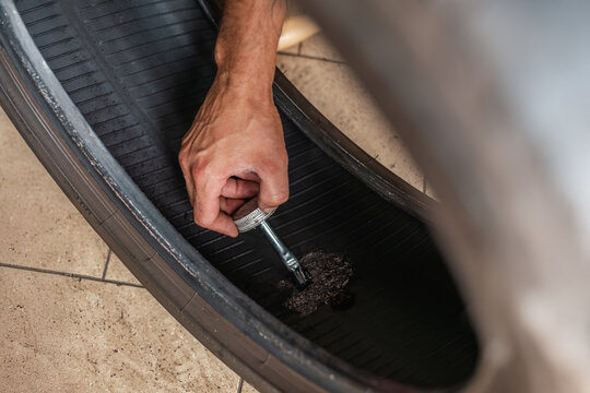 Mechanic applying vulcanizing cement to repair a tire. Professional car maintenance.