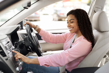 Road Playlist. Side View Profile Portrait Of Happy Black Woman Driving Car And Listening To Music On Auto Audio System, Checking Automobile Options During Test Drive Pushing Button On Turning On Radio