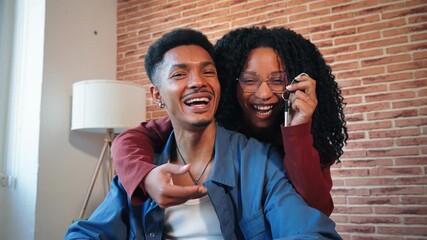 A delighted couple happily engaging in a light-hearted moment together while joyfully showcasing their new keys to one another, embracing the excitement of homeownership and their shared journey.