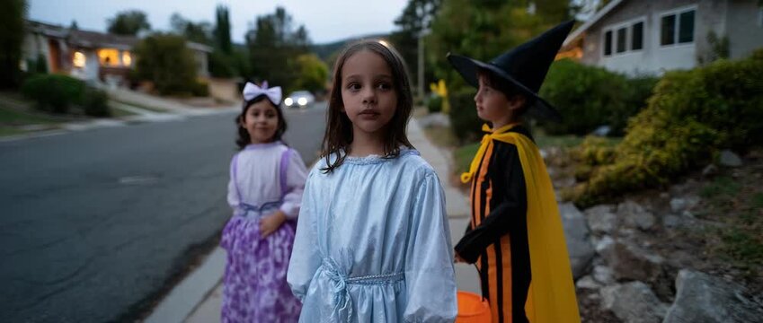 Kids in costumes eagerly trick-or-treating on Halloween evening.