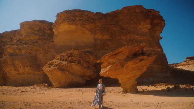 Woman tourist in Saudi Arabia, walking in desert among the sand rocks in AlUla. Tourism in Al Ula, Arabic Peninsula scenic nature.