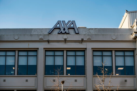 The prominent blue and white AXA Insurance logo is mounted atop a corporate office building in Dublin against a clear, bright blue sky.