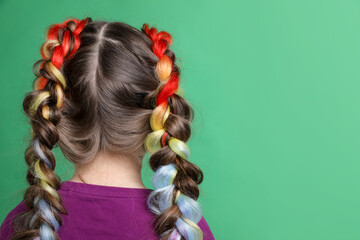 Cute girl with stylish braids on green background, back view. Space for text