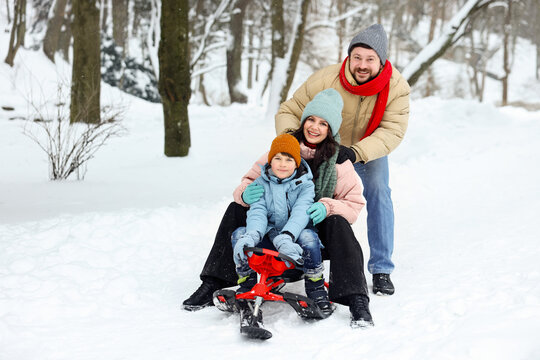 Happy family having fun with sledge outdoors on winter day, space for text