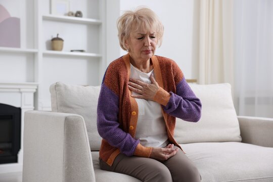 Heart attack. Senior woman suffering from pain in chest indoors
