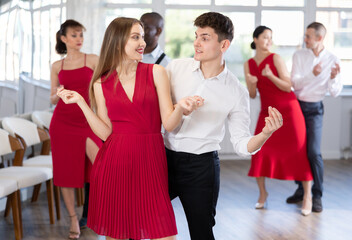 Fototapeta premium Woman paired with man practices movements of twist dance and trains to perform movements during lesson in choreography studio.
