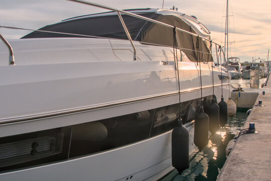 Side view of a premium motor yacht with black fenders protecting the hull 