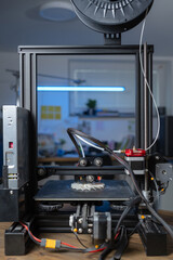 A 3D printer produces a plastic prototype in a clean workspace using additive manufacturing.