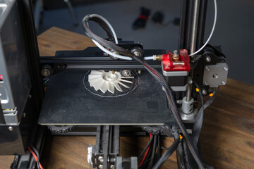 A modern 3D printer works on a plastic prototype in a clean workspace, focusing on the extruder and print bed during the process.