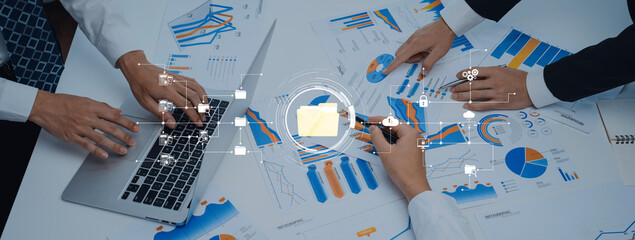 Team members collaborate on data analysis in a modern workspace, surrounded by various charts and graphs to enhance business strategy and financial planning. Trope