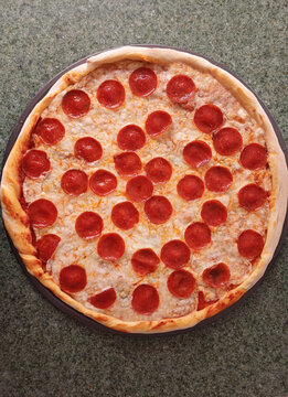 Pizza redonda de queso y pepperoni hecha en casa, toma vertical. Fotograf&iacute;a gastron&oacute;mica hecha con el tel&eacute;fono m&oacute;vil.