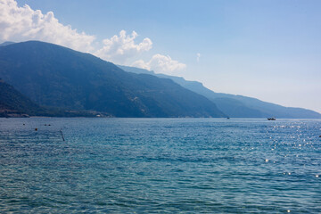 Mountain coastline with calm blue sea under clear sky.