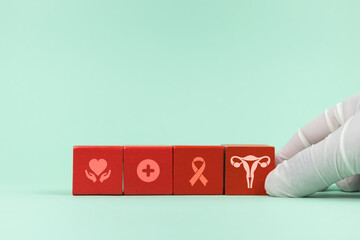 Gynecologist places wooden cubes with a uterus icon and medical icons. Concept of cervical cancer...