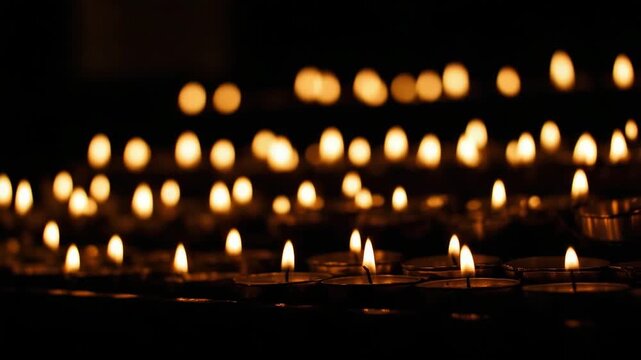 many small candle flames burning in a dark space, long rows of candles forming leading lines, warm flickering light, deep shadows