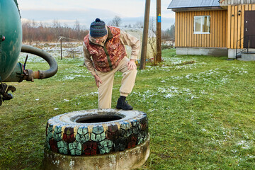Sewage vacuum truck operation observed by sanitation worker inspecting circular cesspit opening before connecting hose for scheduled Honey sucker waste extraction.