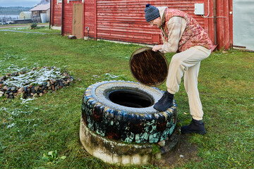 Sanitation worker preparing septic tank access by lifting cover over concrete ring before sewage pumping during routine wastewater management operation.