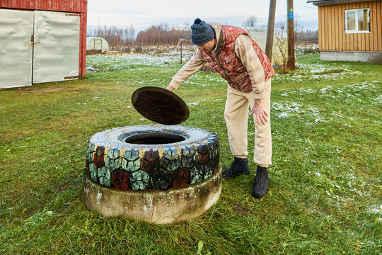Examining septic tank opening by cesspit emptier during sanitation service while Sewage accumulation is visually assessed for scheduled wastewater removal.