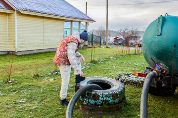 Pumping sewage from septic tank using vacuum truck hose as worker controls suction process and ensures complete removal of liquid waste.
