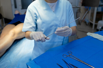 Surgeon readying instruments for vascular leg surgery in clinic.
