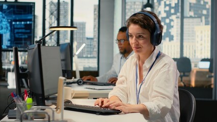Developer listening music while working in AI startup training predictive models for language processing tasks. Tech expert wearing audio headphones uses technical expertise for IT tasks, camera B