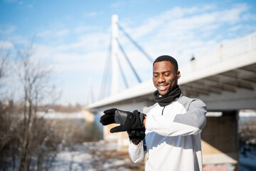 African american man checking fitness tracker during winter workout