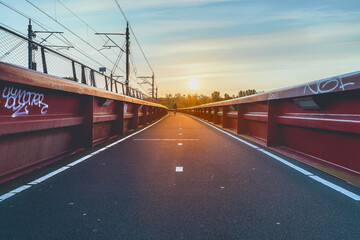 Sunset paints a path over a tranquil bridge surrounded by nature and urban elements