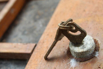 Old rusty key installed in the keyhole on a worn wooden door.