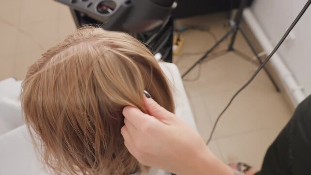 Topdown root smoothing with hairdryer, stylist refines part and fits lace cap, comb and fingers shape hairline, overhead view shows tools, workstation and tile floor, calm focused technique