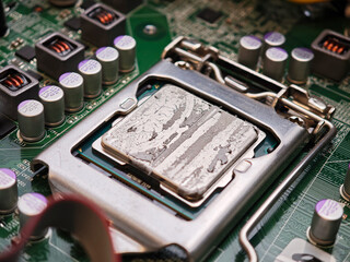 Dried cracked thermal paste on CPU in motherboard socket with cooler removed, macro closeup of computer processor and LGA bracket, repasting maintenance, overheating repair troubleshooting, no people