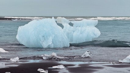 dramatic and out of this world landscape of blue icebergs and diamond like ice washed ashore in the black sands of Diamond Beach in south Iceland
