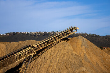 A conveyor machine and a large mound of dirt and gravel at a construction site